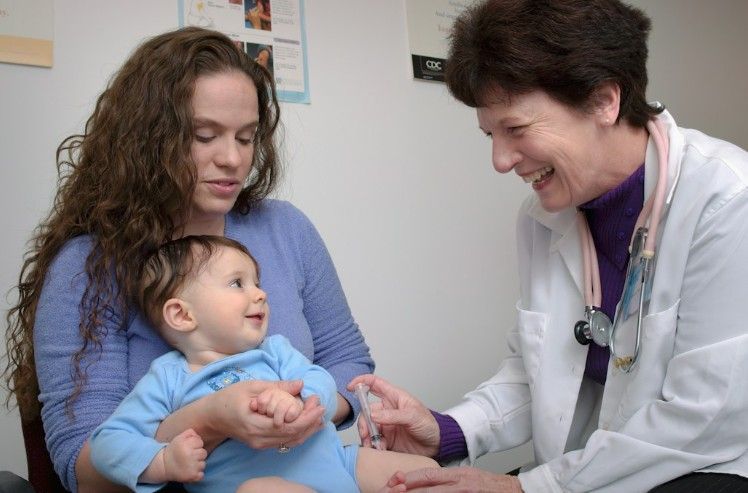 Smiling pediatrician examining a baby held by its mother | See a Pediatrician in Turkey | Online Doctor | E-rx.online